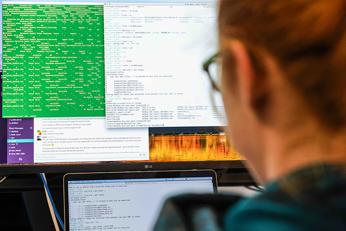 A woman is looking at a computer screen with code on it